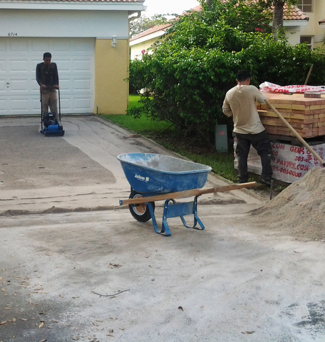 people with sandand pavers on a driveway